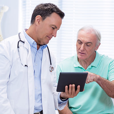 Male Doctor with patient discussing items on a tablet device