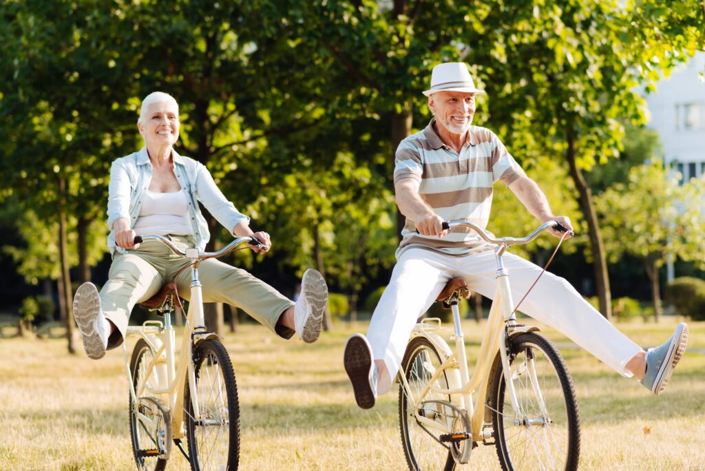 couple in their late 50s riding bikes on a sunny day in the park