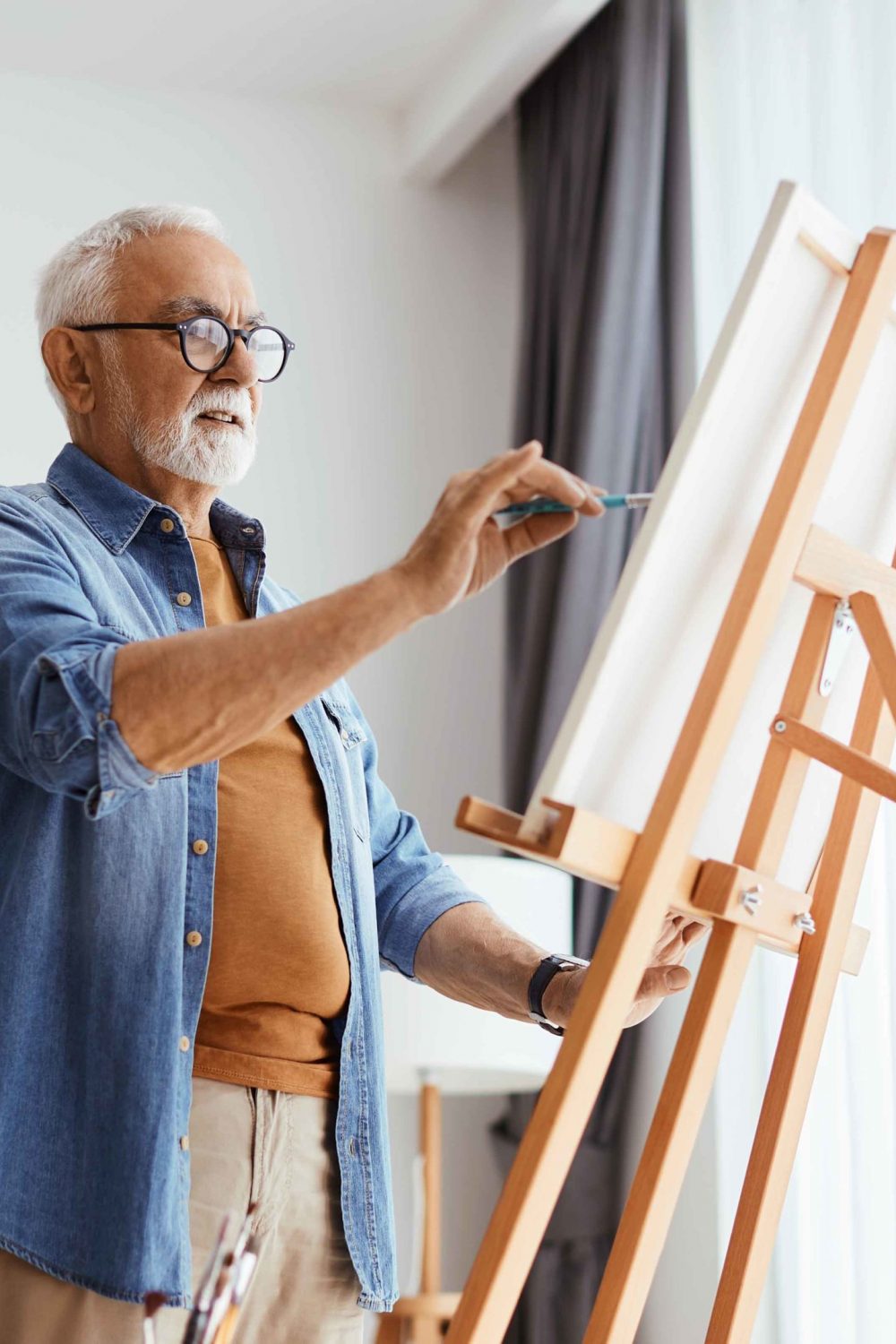 Senior man painting on canvas while enjoying creative time at home.